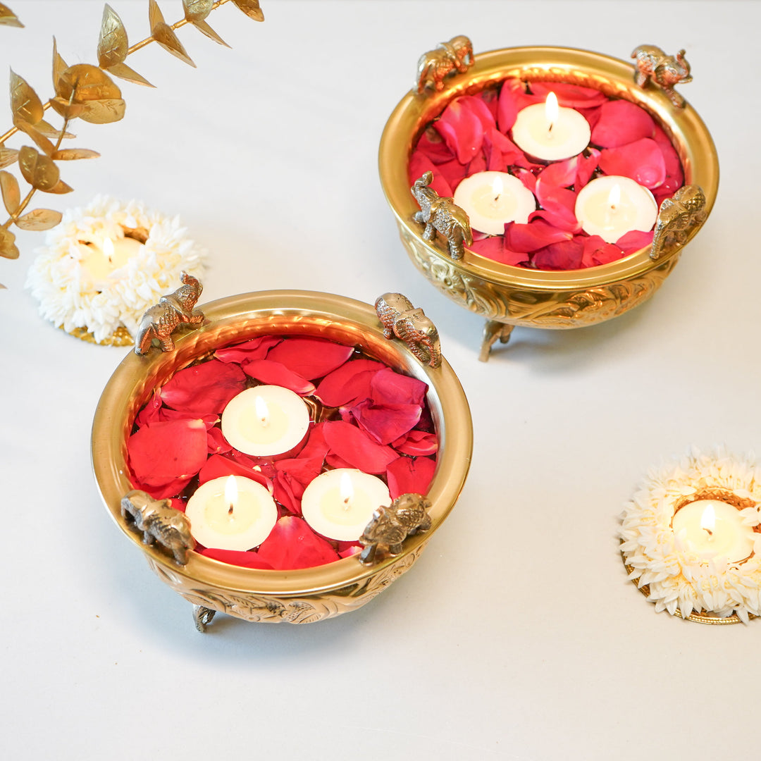 Two elephant brass urlis filled with red rose petals and floating tealights