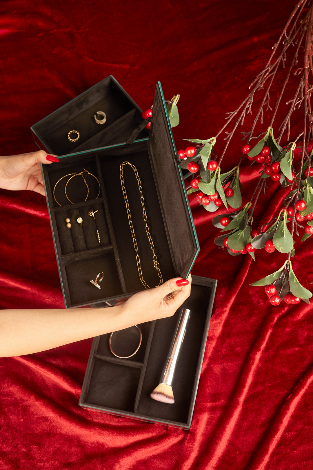 Open three tier mirror glass jewellery box with black suede compartments holding jewellery